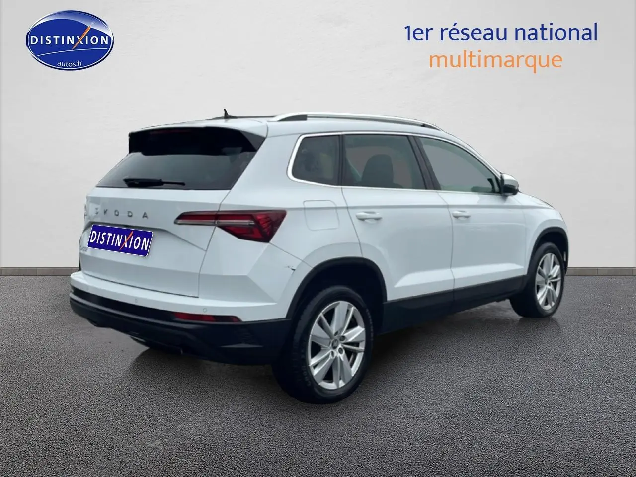 Vue 3/4 arrière droite d'un Skoda Karoq blanc glacial avec jantes alu et vitres arrière surteintées.