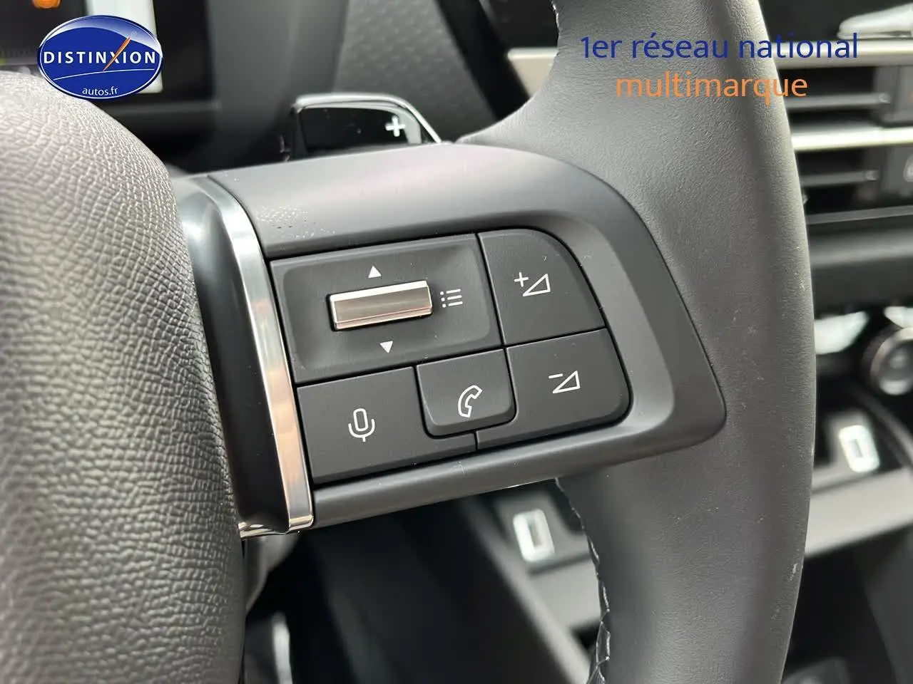 Gros plan sur les commandes vocales et téléphone du volant cuir d'une Citroën C4 hybride noire 2025.