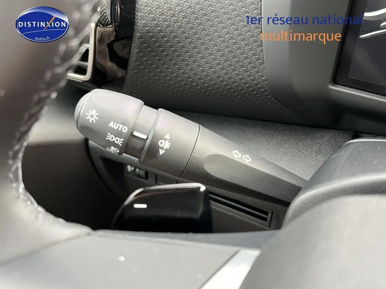 Gros plan sur la manette de clignotants et feux du tableau de bord d'une Citroën C4 noire métal 2025.