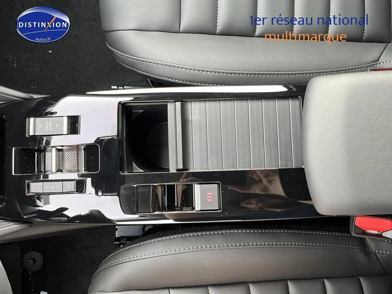 Vue plongeante sur la console centrale noire brillante de la Citroën C4 hybride 2025 avec commandes de boîte automatique et accoudoir cuir.