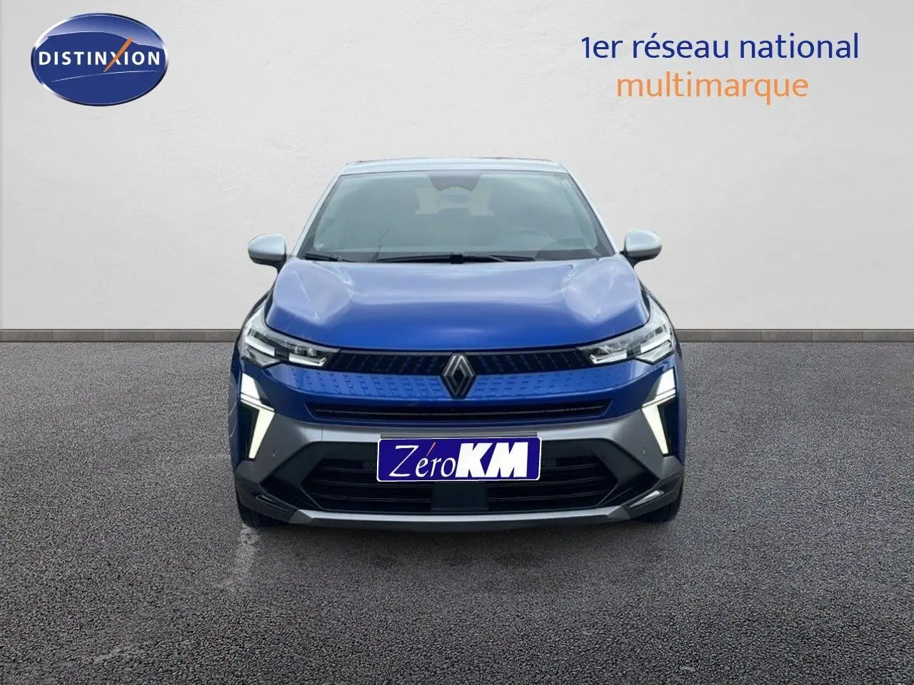 Vue frontale d'un Renault Captur E-Tech hybride bleu Iron Metal avec toit gris, éclairage LED distinctif allumé.