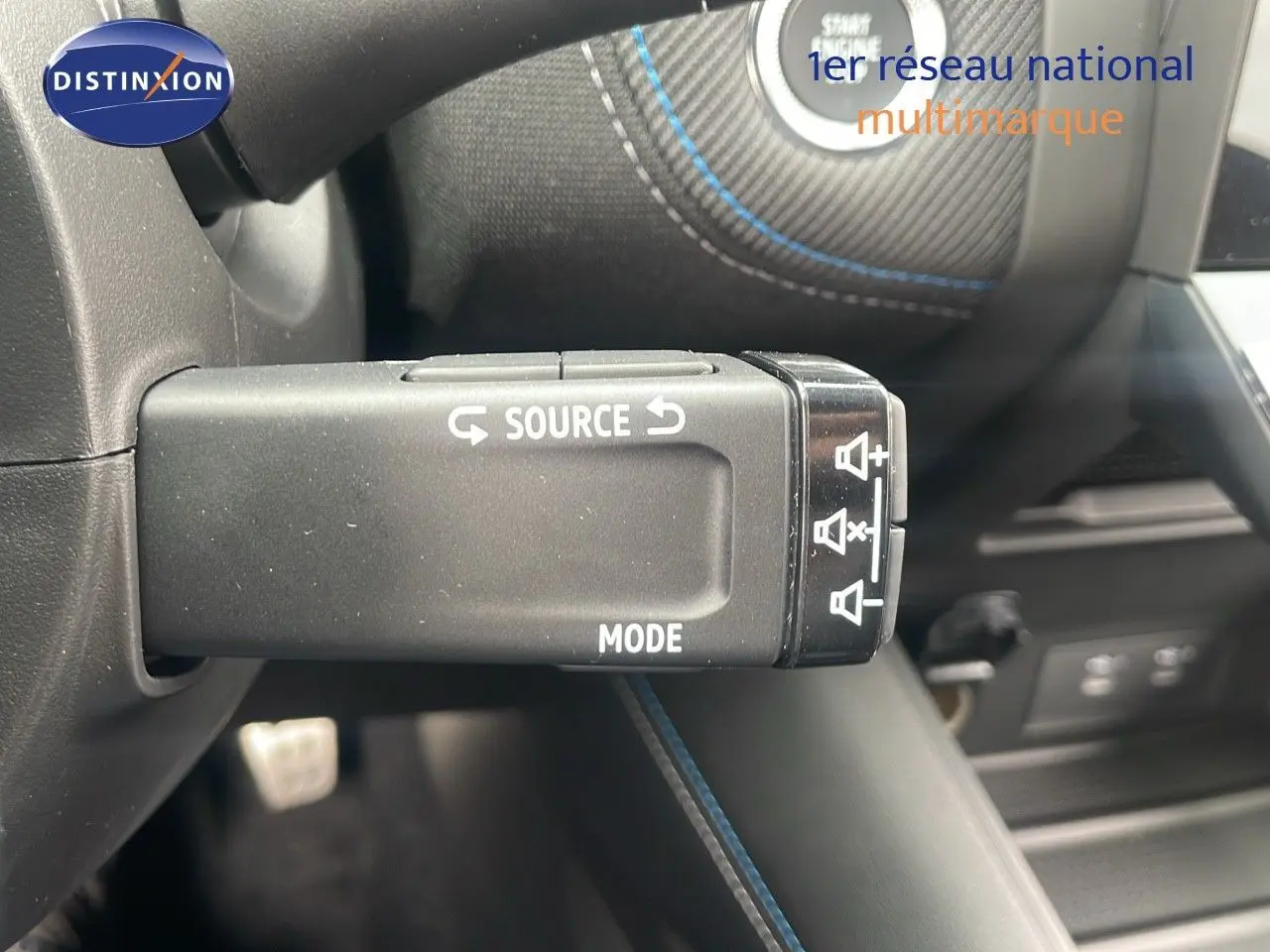 Gros plan sur la commande au volant du Renault Captur E-Tech hybride 2025, avec surpiqûres bleues et finition noire.