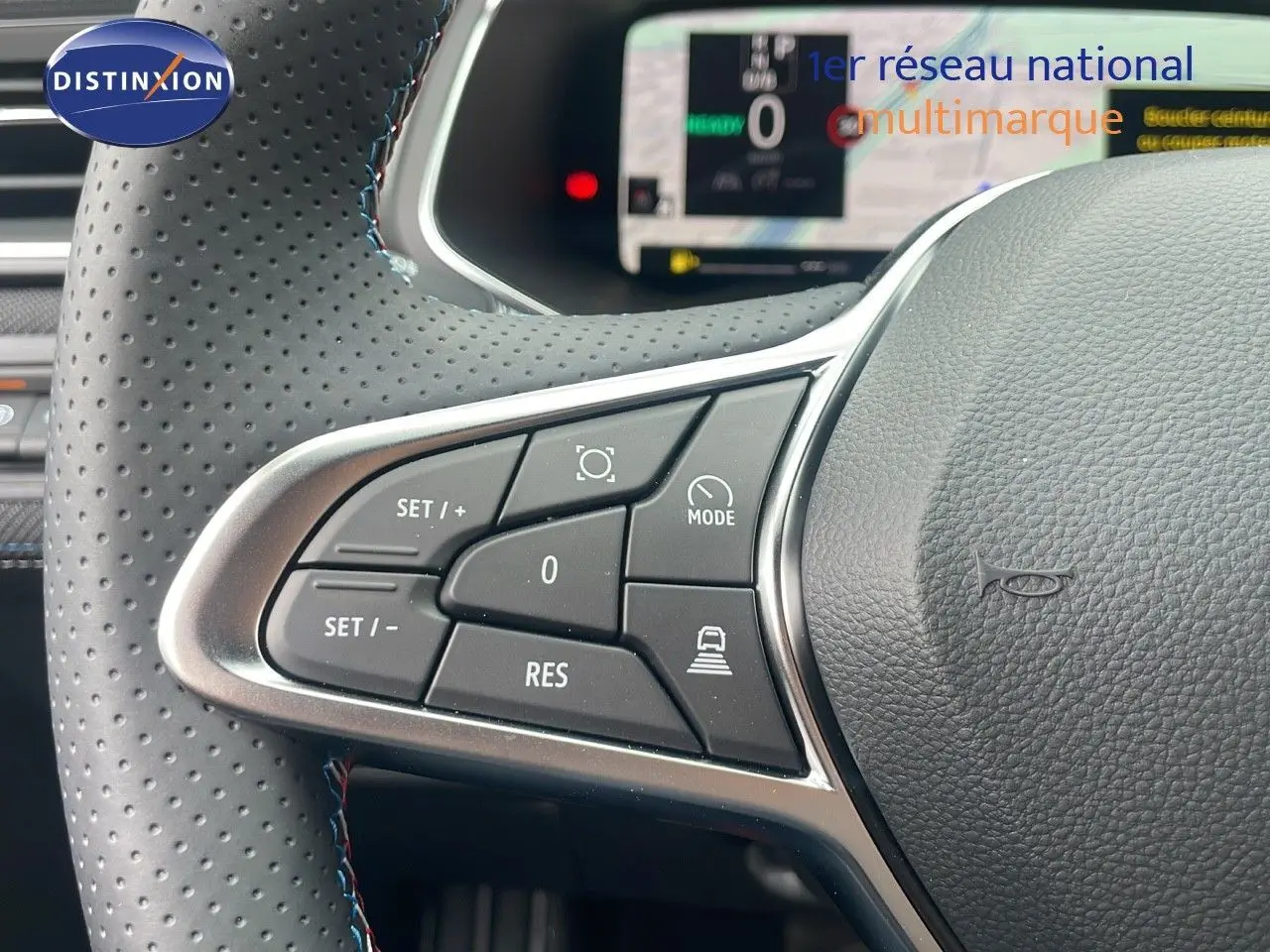 Gros plan sur les commandes au volant du Renault Captur E-Tech hybride 2025, cuir perforé noir avec surpiqûres bleues.