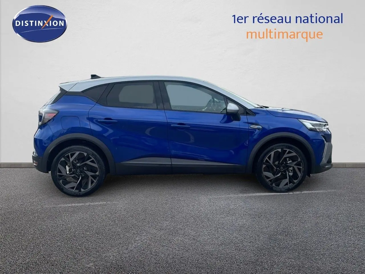 Profil droit d'un Renault Captur E-Tech hybride bleu Iron Metal avec toit gris, roues alliage noires et lignes modernes.