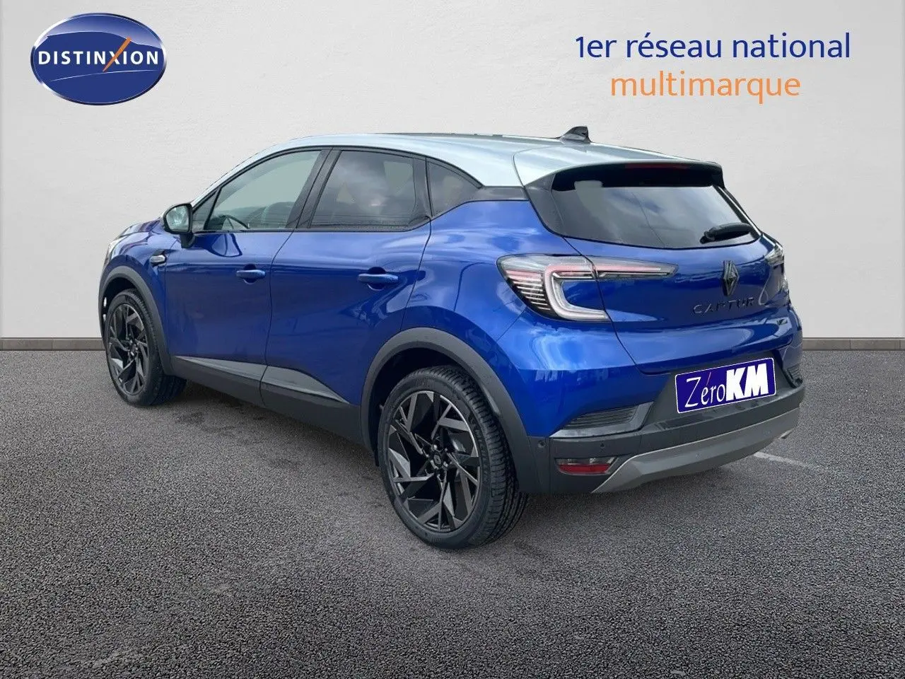 Renault Captur E-Tech hybride bleu Iron avec toit gris, vue 3/4 arrière côté gauche, jantes noires distinctives.