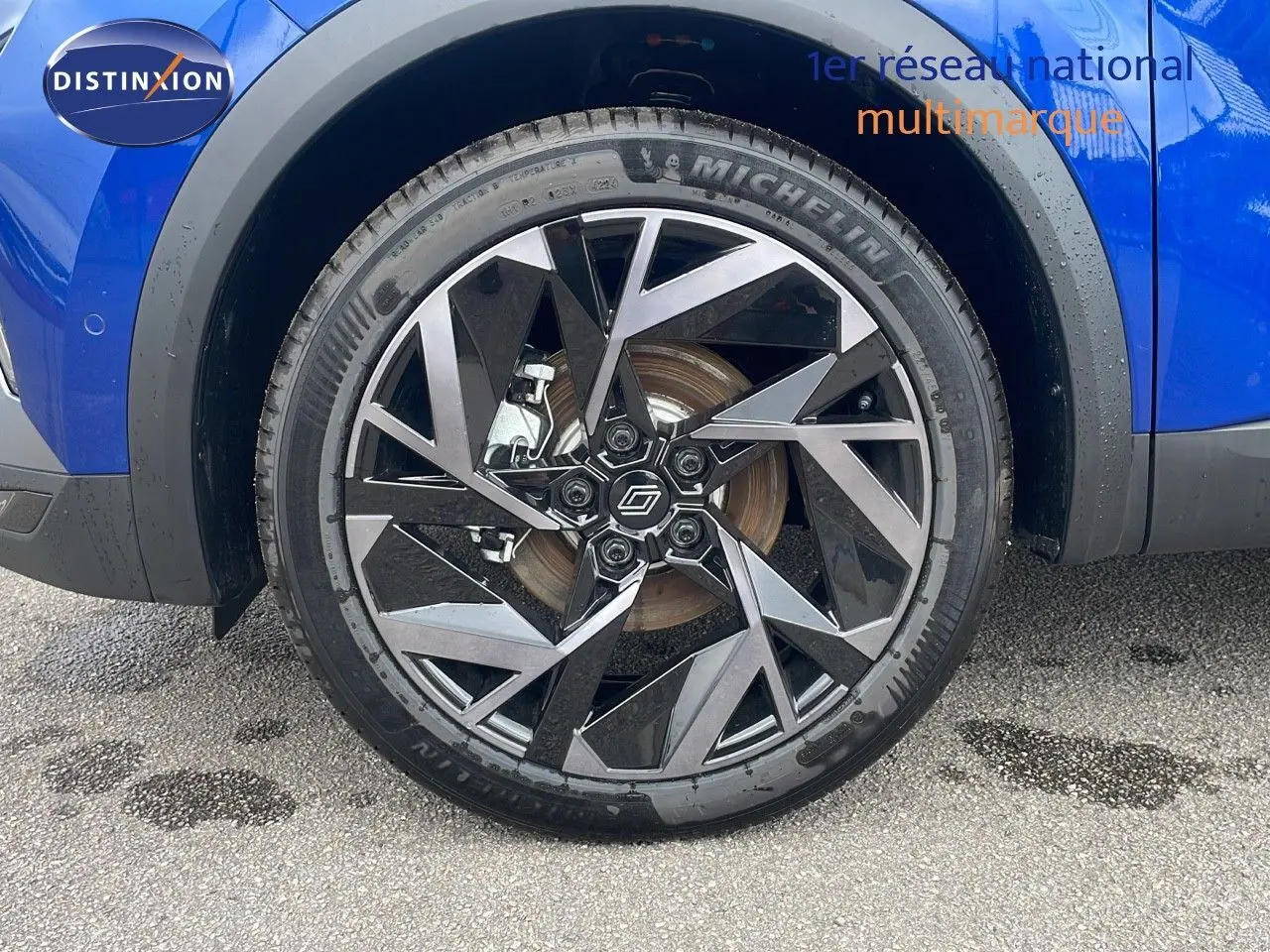 Gros plan sur la roue avant gauche avec jante noire et argent du Renault Captur bleu Iron Metal 2025.