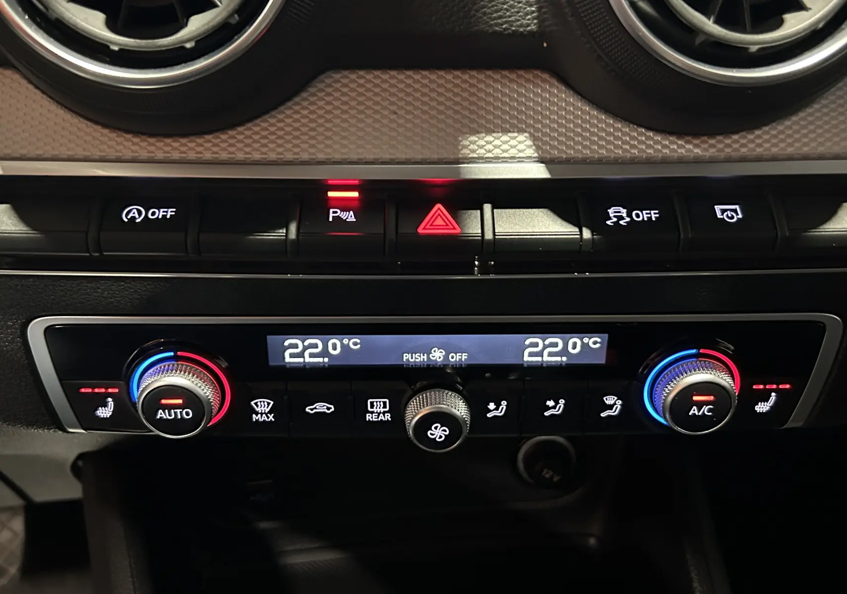 Gros plan sur le bouton de réglage de la climatisation et siège chauffant dans l'Audi Q2 noir métal 2023.