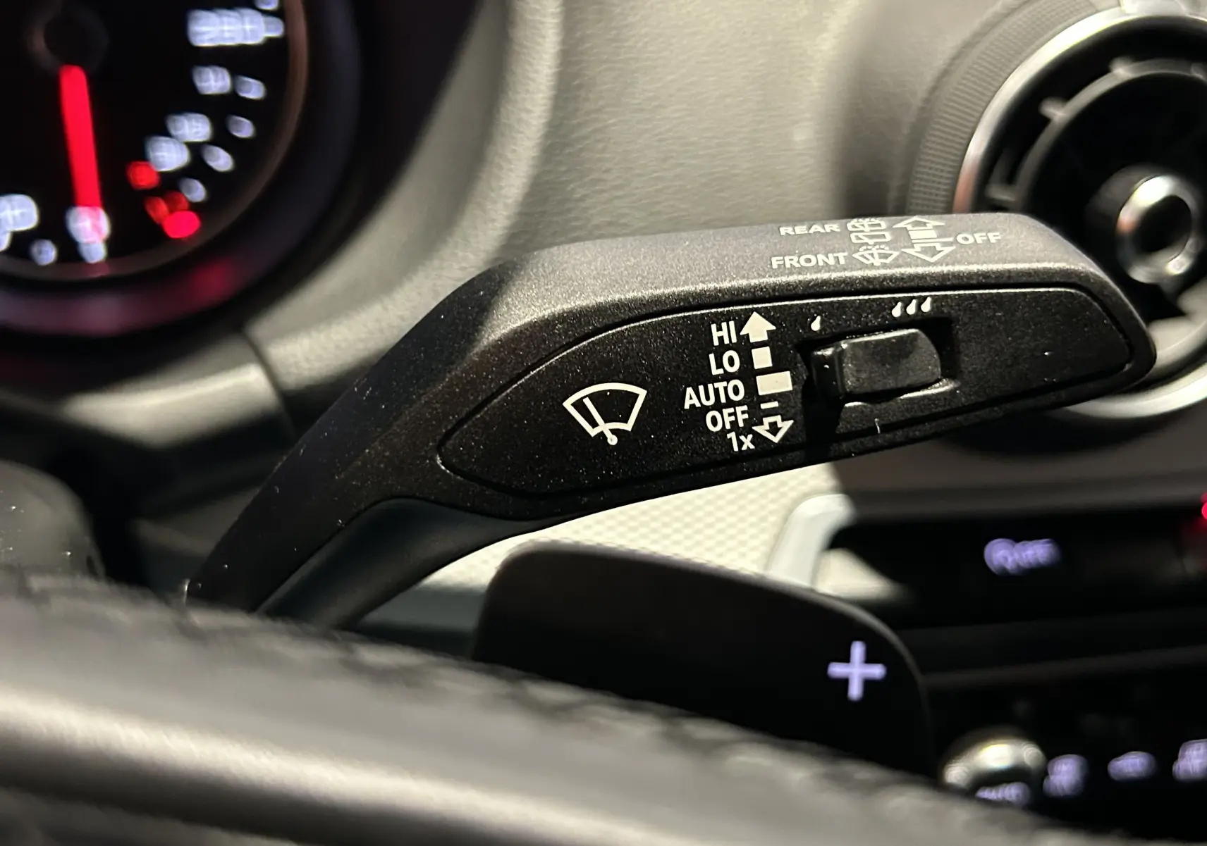 Gros plan sur la commande de régulateur de vitesse à gauche du volant en cuir noir de l'Audi Q2 2023.