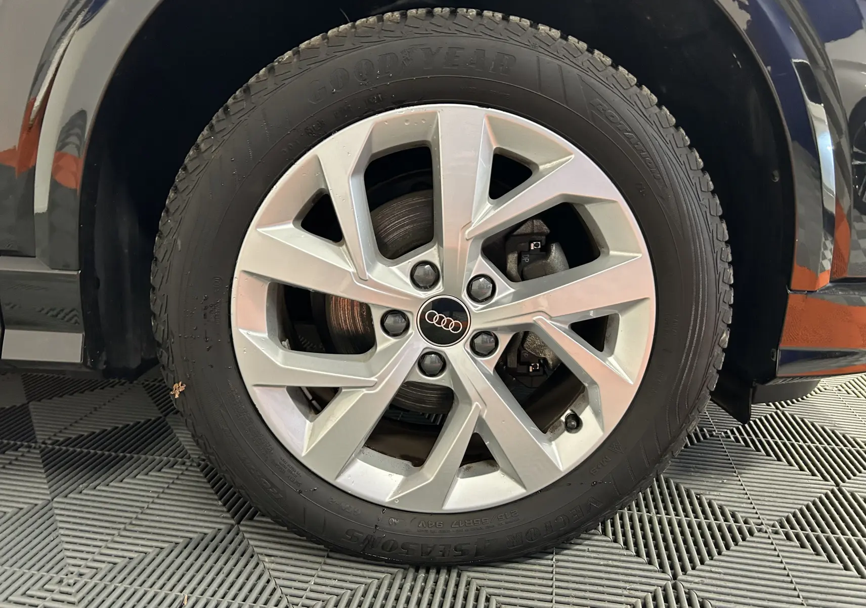 Gros plan sur la roue avant gauche d'un Audi Q2 noir métal 2023 avec jante alliage et logo Audi central.