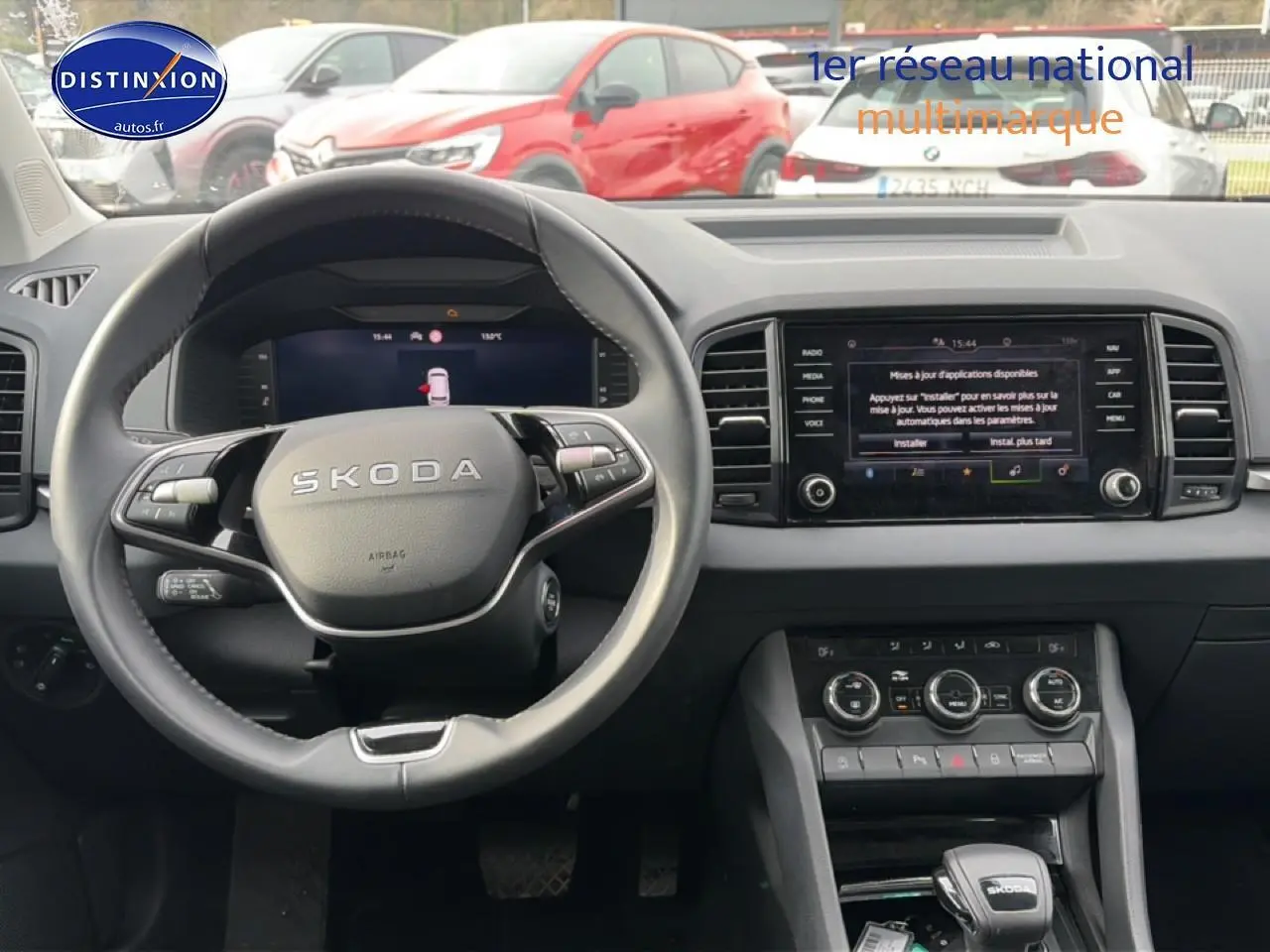 Vue intérieure du tableau de bord et volant cuir du Skoda Karoq blanc glacial, avec écran tactile central allumé.