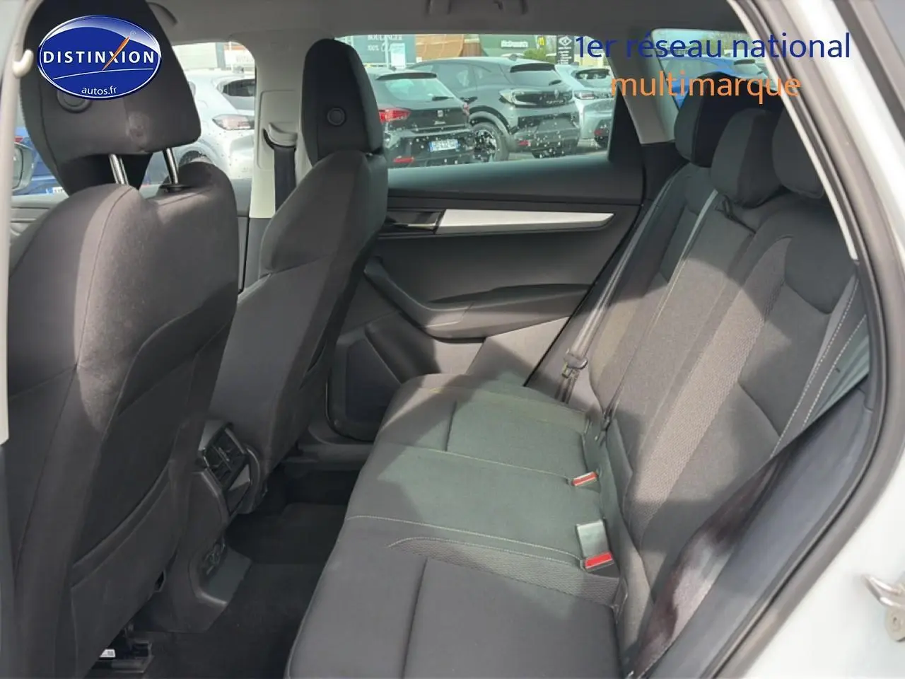 Vue latérale intérieure des sièges arrière noirs du Skoda Karoq blanc glacial, avec accoudoirs et habillage sombre.