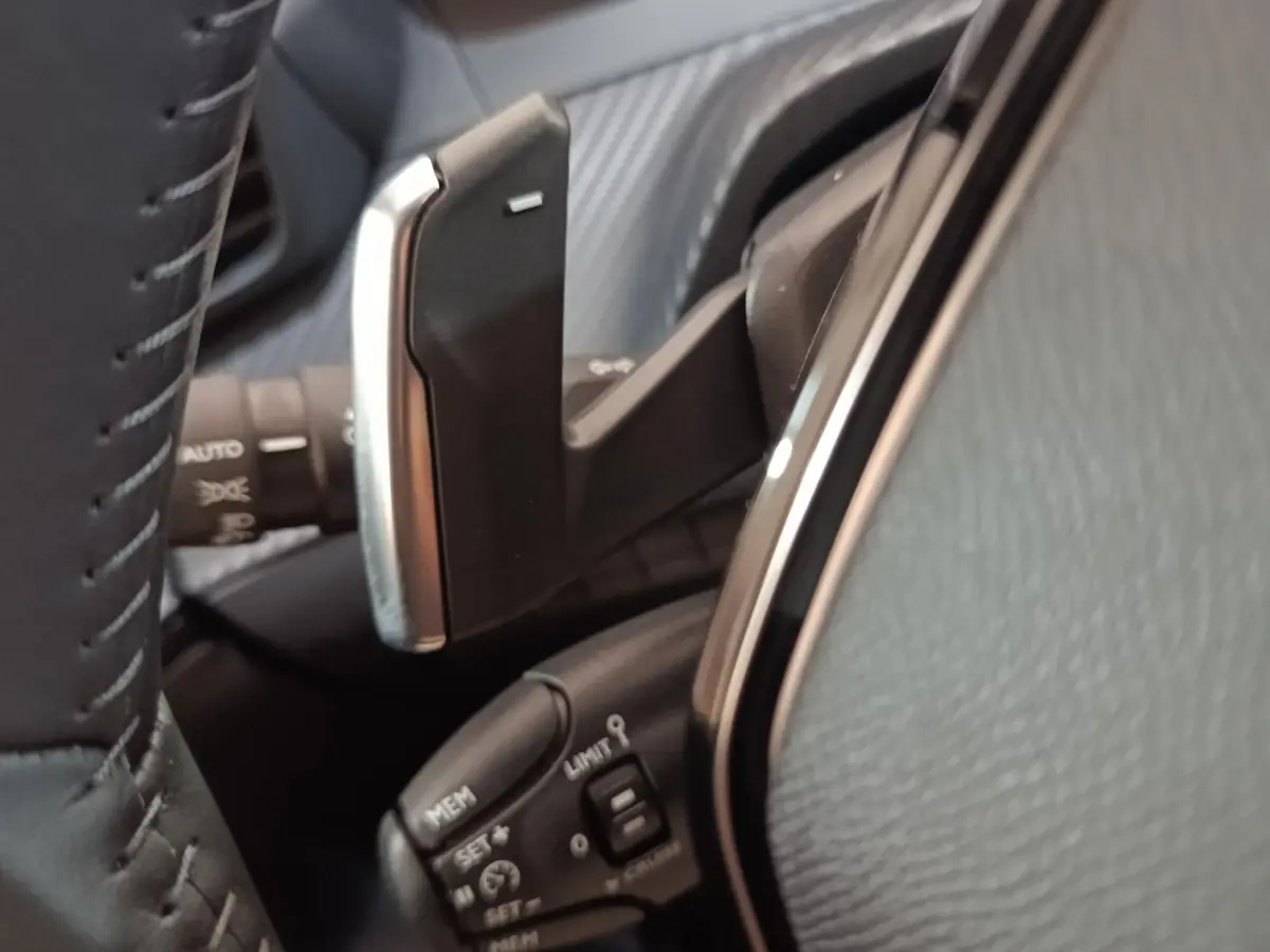 Gros plan sur le volant cuir et les commandes de régulateur de vitesse de la Peugeot 208 Hybrid gris clair.