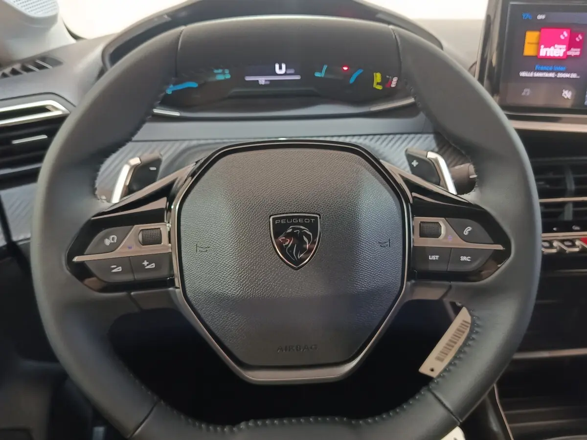 Volant cuir noir de Peugeot 208 Hybrid 2025 vu de face avec commandes multifonctions et tableau de bord numérique.