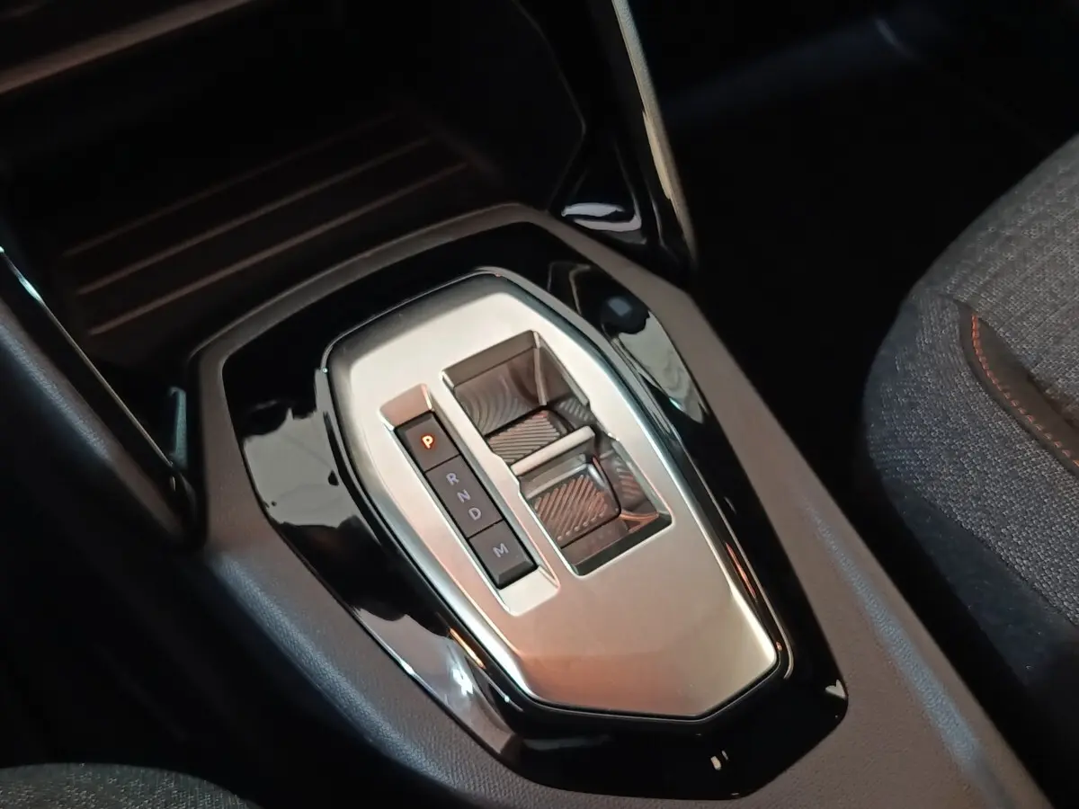 Gros plan sur la console centrale noire et argentée avec levier de vitesses automatique de la Peugeot 208 Hybrid 2025.