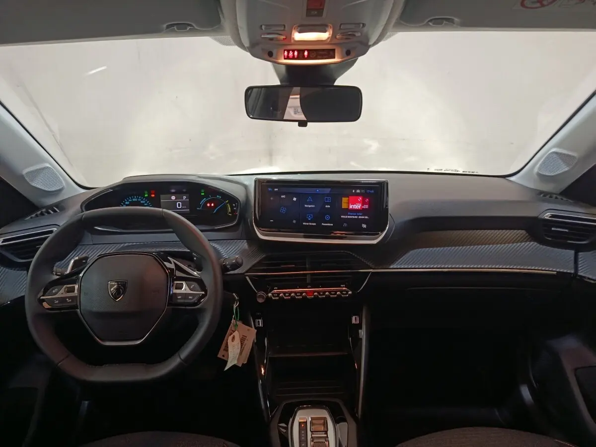 Vue frontale de l'intérieur de la Peugeot 208 Hybrid gris clair, avec tableau de bord numérique et écran tactile central.