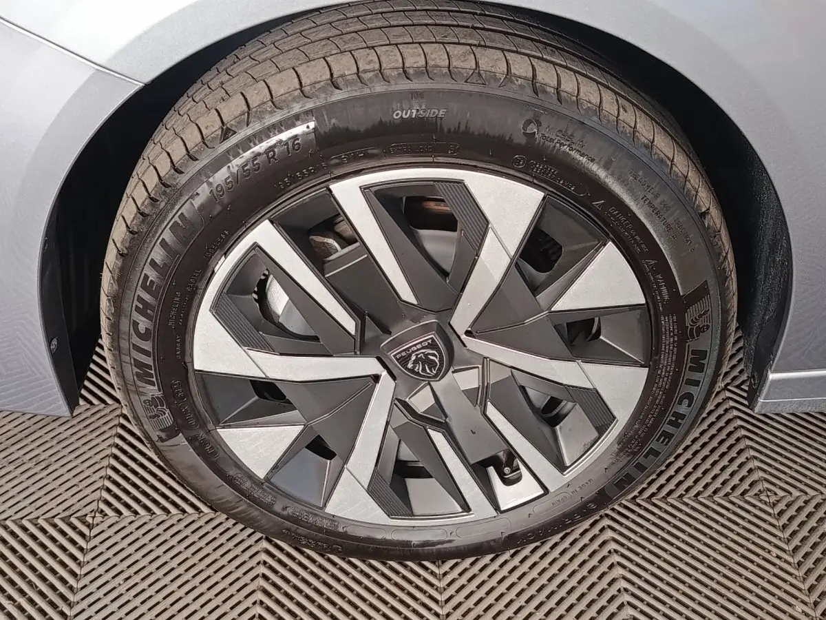 Gros plan sur la roue avant gauche grise d'une Peugeot 208 Hybrid 100 e-DCS6 Style avec jante au design géométrique.