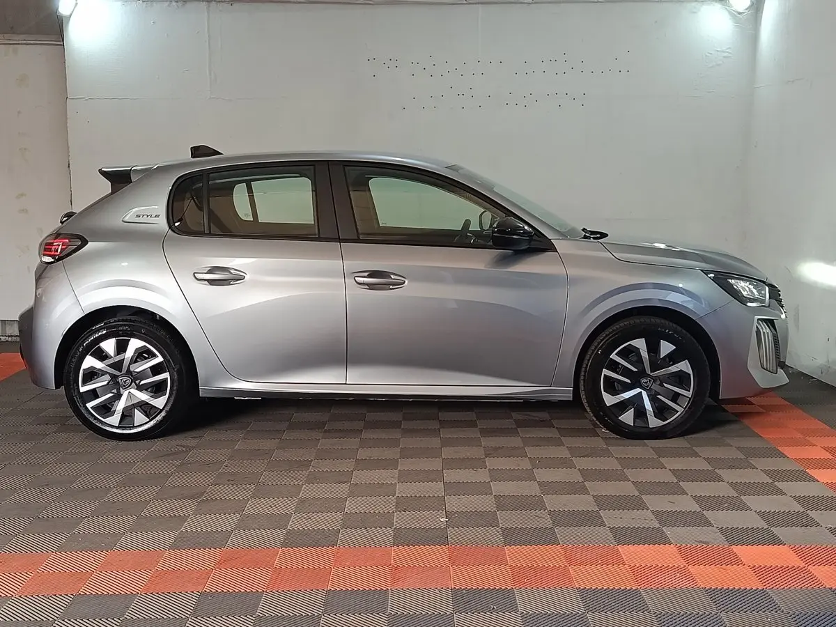 Peugeot 208 Hybrid gris clair vue de profil côté gauche, avec jantes alliage et badge Style visible à l'arrière.
