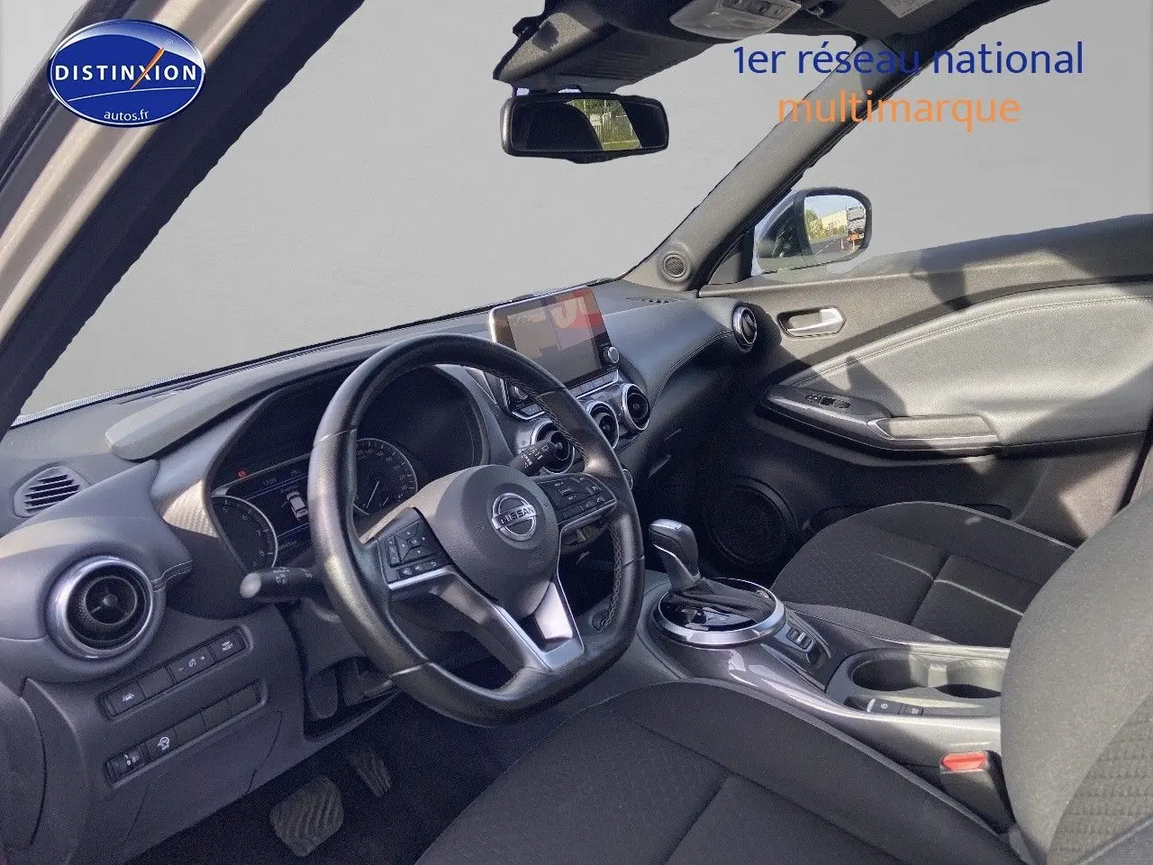 Intérieur noir du Nissan Juke 2021, vue côté conducteur montrant volant, tableau de bord et console centrale.