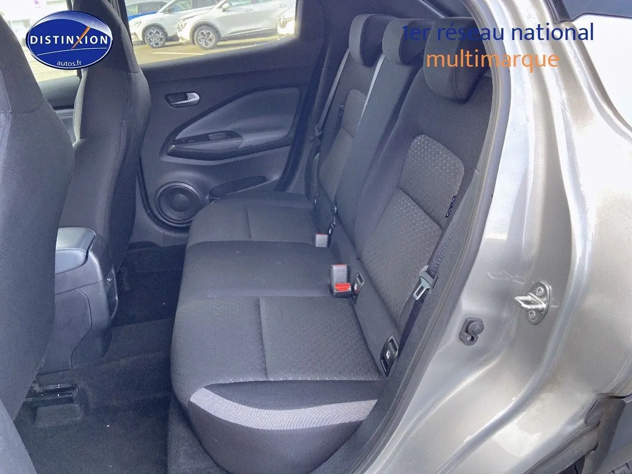 Vue côté droit sur l'intérieur arrière du Nissan Juke gris clair, mettant en valeur les sièges en tissu noir.