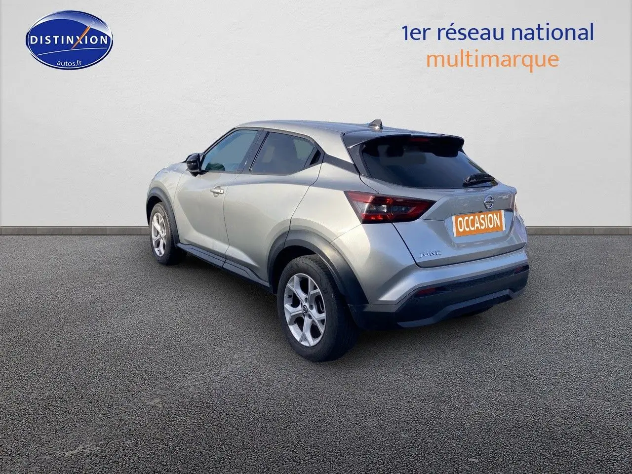 Nissan Juke gris clair vu en 3/4 arrière droit, avec jantes alliage et vitres teintées.