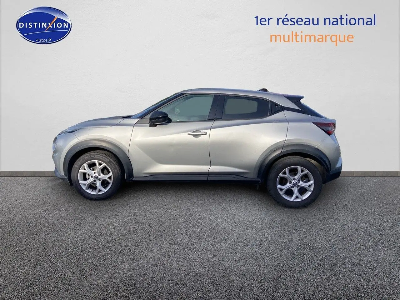 Profil côté gauche d'un Nissan Juke gris clair 2021 avec jantes alliage et protections noires sur les passages de roue.