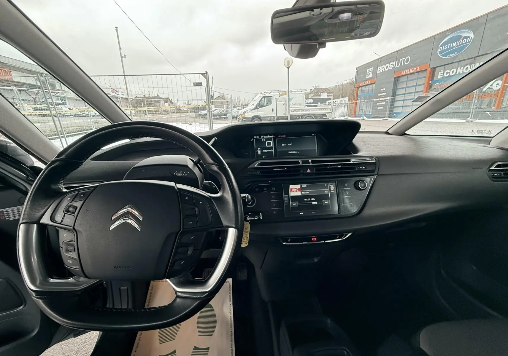 Vue intérieure centrée sur le tableau de bord et le volant de la Citroën C4 Picasso gris platinium, avec écran tactile et commandes au volant.