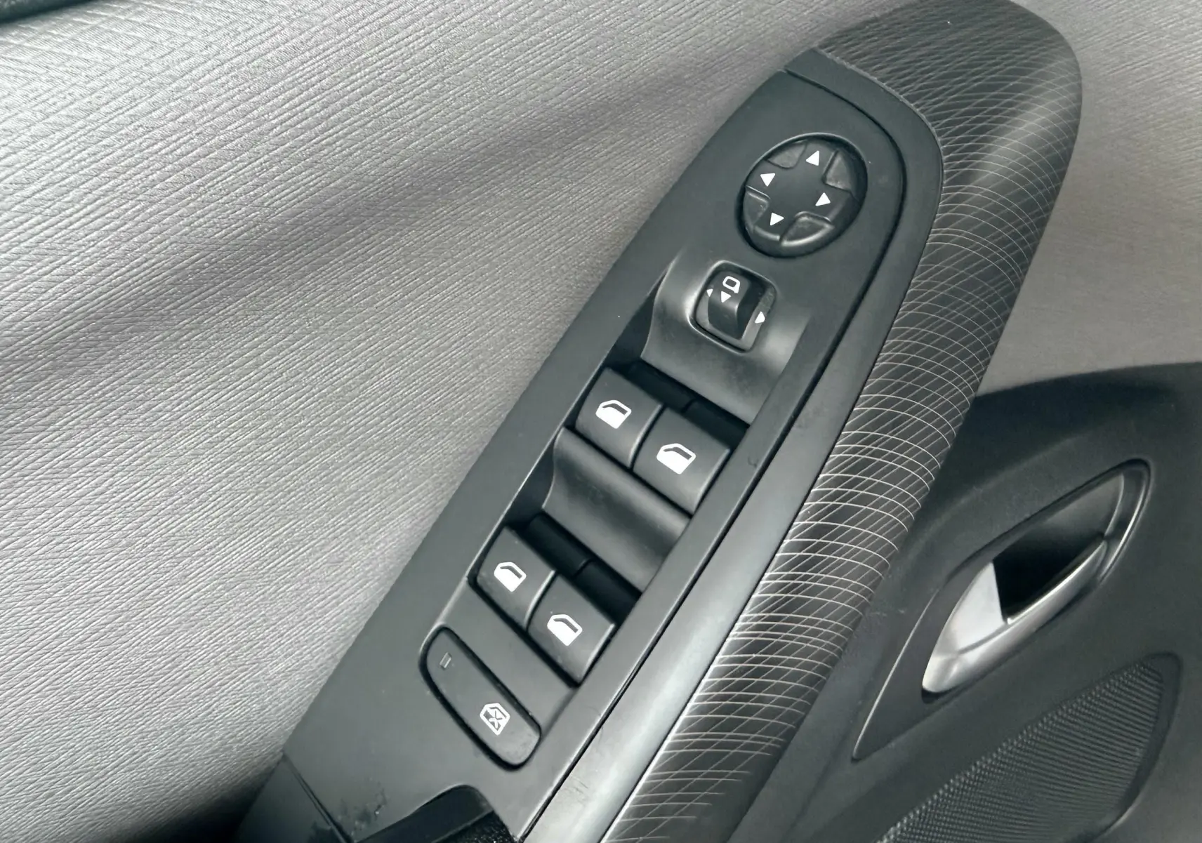 Gros plan sur les commandes de lève-vitres et rétroviseurs sur la porte côté gauche d’une Citroën C4 Picasso.