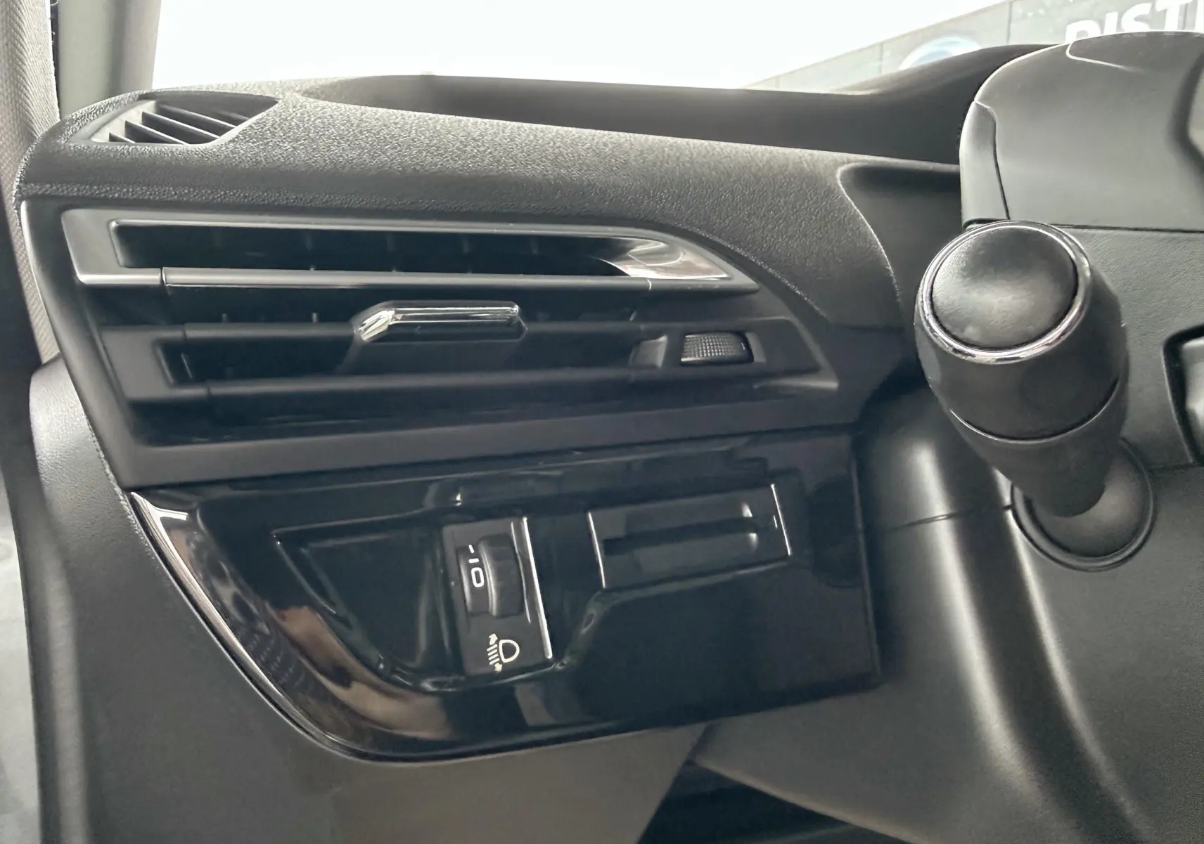 Détail du tableau de bord côté gauche avec commande de réglage des phares sur Citroën C4 Picasso 2015.