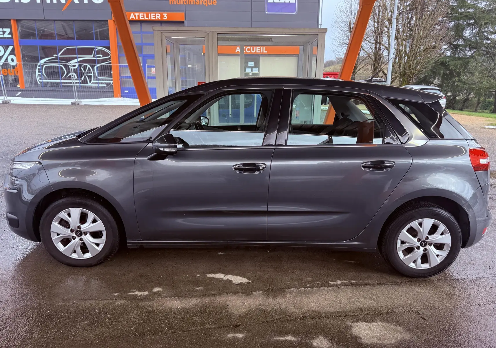 Vue latérale droite d'une Citroën C4 Picasso gris platinium métallisé, avec jantes alliage et lignes fluides.