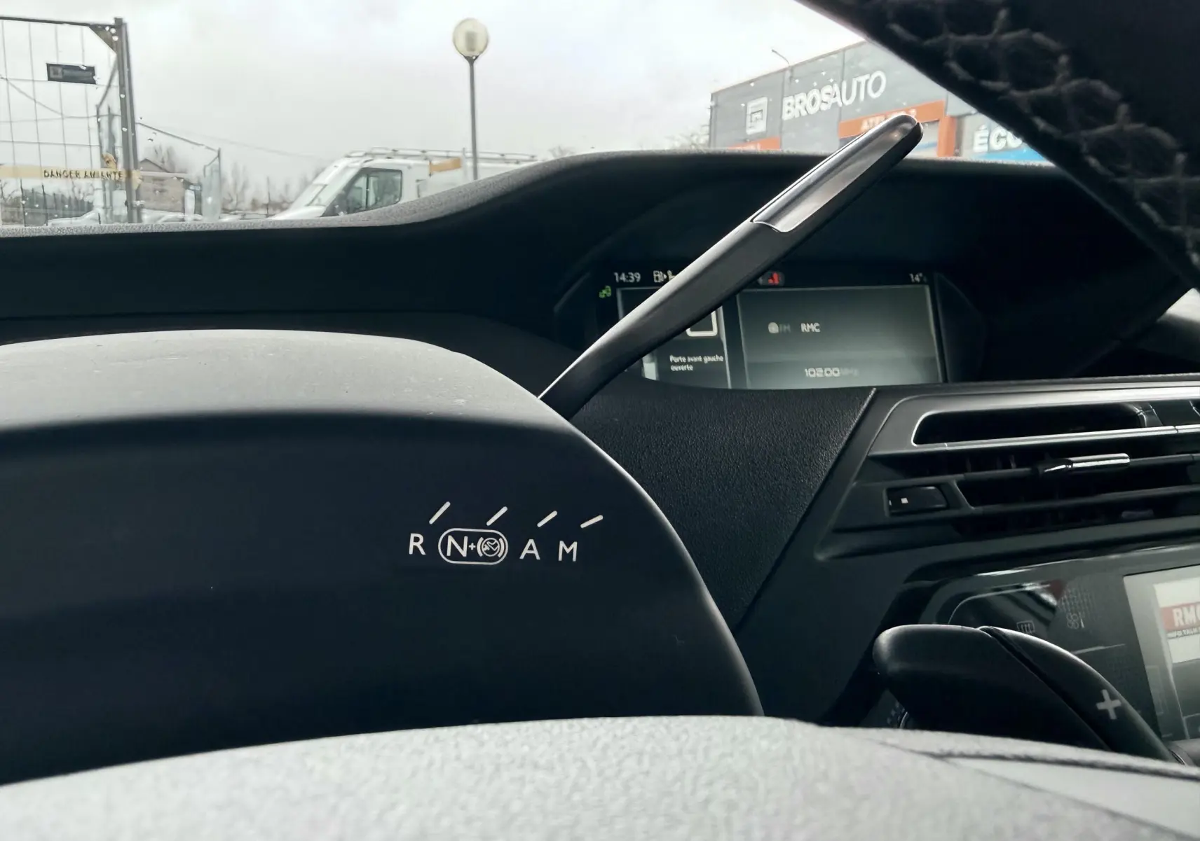 Gros plan sur le tableau de bord noir de la Citroën C4 Picasso, montrant le levier de vitesses et l’écran multifonction.