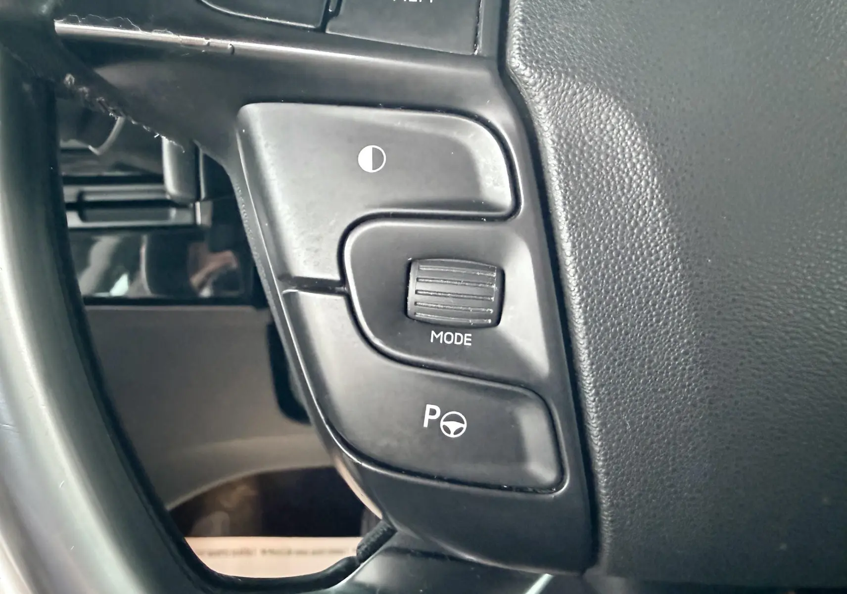 Gros plan sur les commandes de réglage du volant et mode de conduite à gauche du volant d’un Citroën C4 Picasso gris platinium.