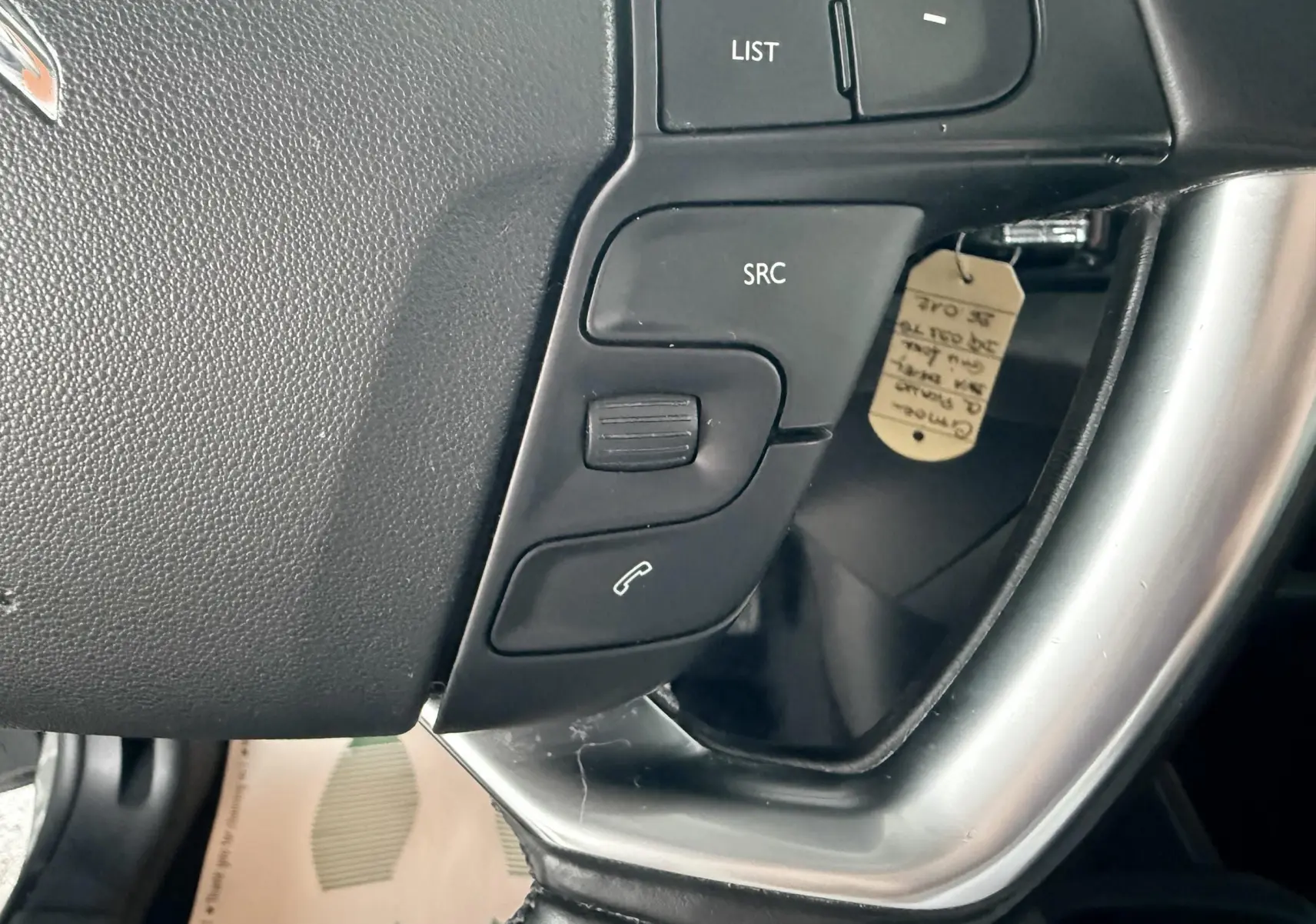 Gros plan sur les commandes gauche du volant d’une Citroën C4 Picasso 2015, finition gris platinium métal.