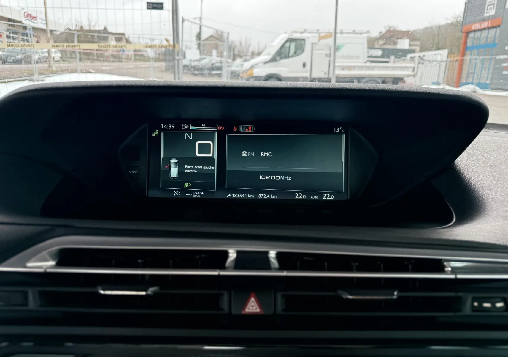 Vue rapprochée du tableau de bord numérique de la Citroën C4 Picasso gris platinium, affichant la radio et l'ouverture de la porte avant gauche.