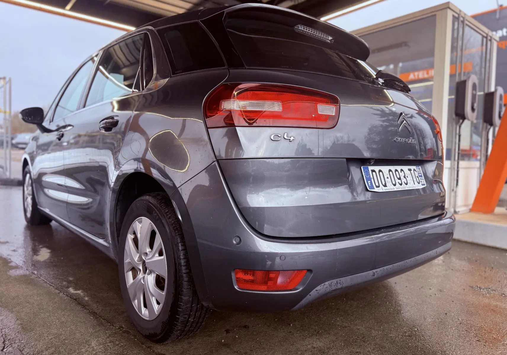 Vue 3/4 arrière droite d'une Citroën C4 Picasso gris platinium métallisé avec feux arrière et plaque d'immatriculation visibles.