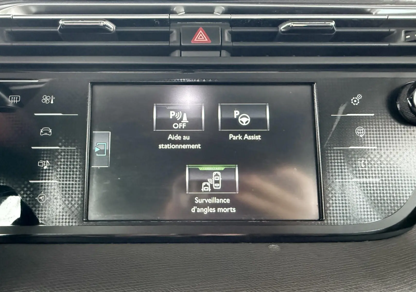 Écran central de la Citroën C4 Picasso gris platinium montrant les aides au stationnement et surveillance d'angles morts.