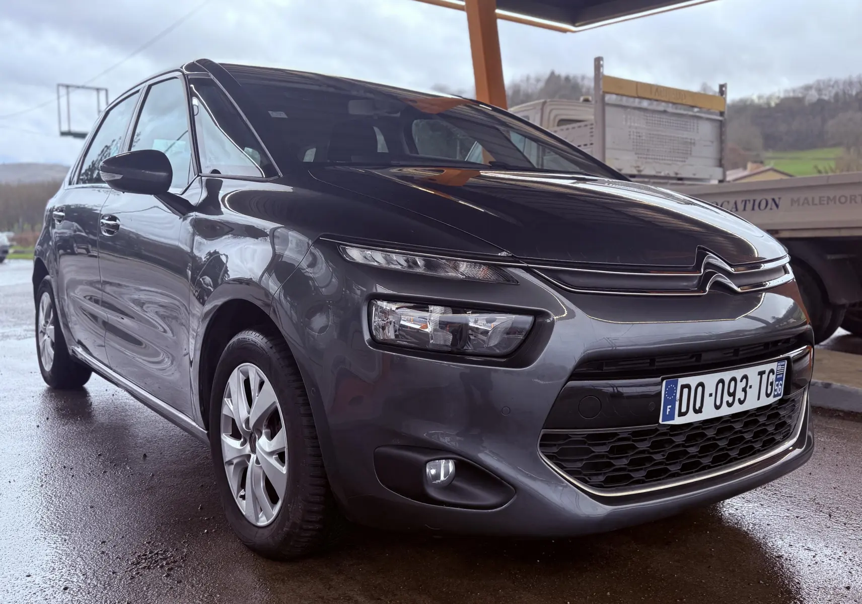 Citroën C4 Picasso gris platinium vue 3/4 avant droit sous abri avec calandre distinctive et phares LED.