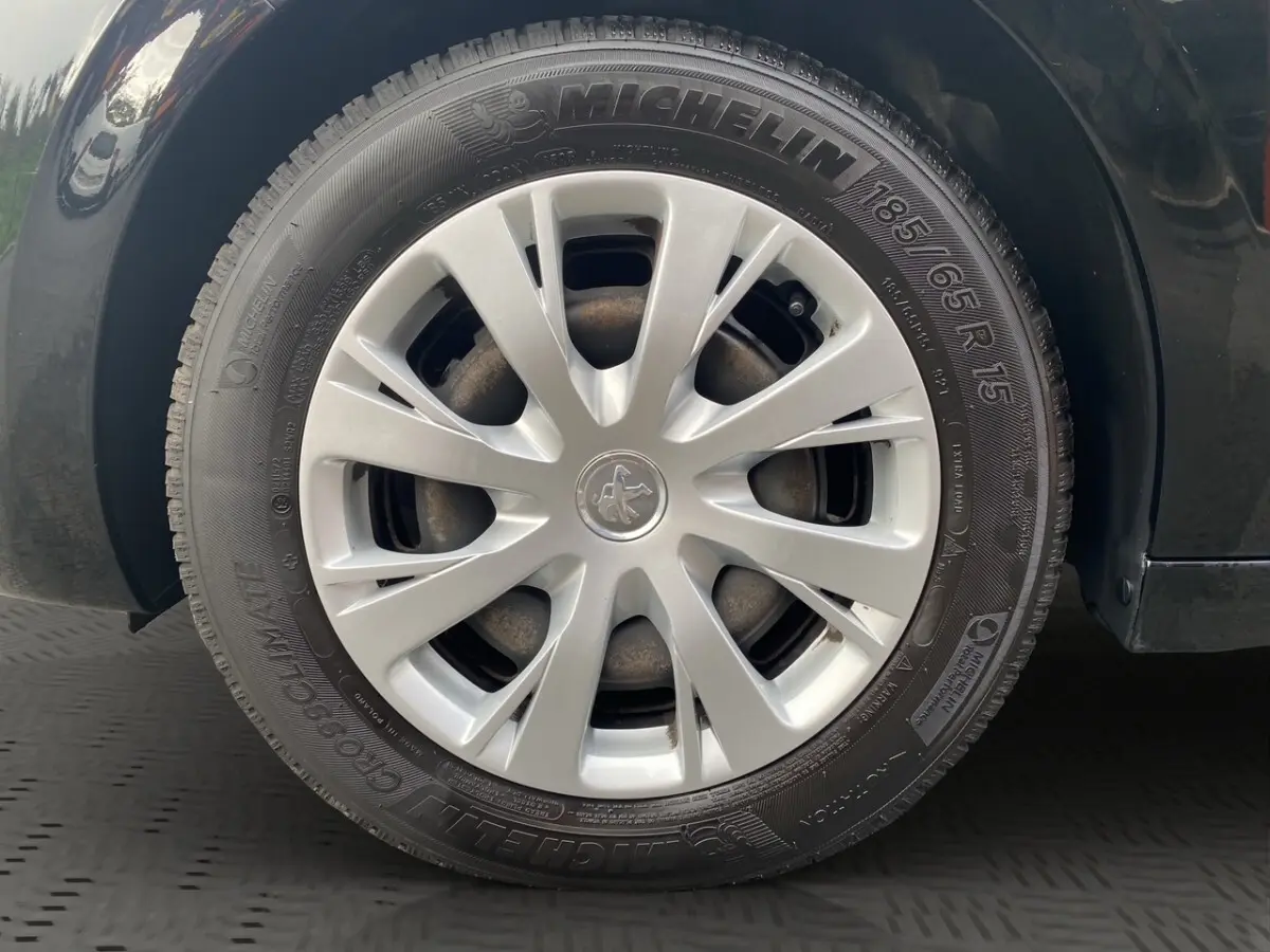 Gros plan sur la roue avant gauche d'une Peugeot 208 Affaire noire, avec jante en alliage et pneu Michelin visible.