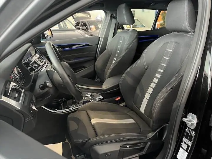 Vue intérieure côté conducteur du BMW X2 noir métal, mettant en valeur les sièges sport et le tableau de bord moderne.