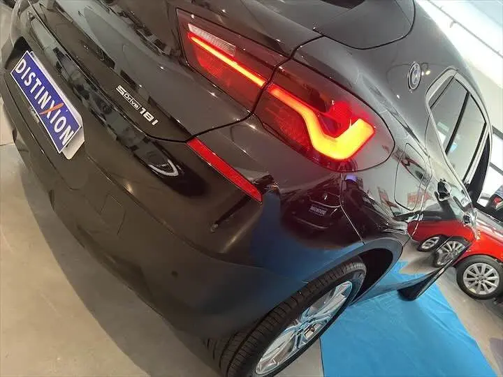 Vue 3/4 arrière droite d'un BMW X2 noir métal avec feux arrière allumés dans un showroom.