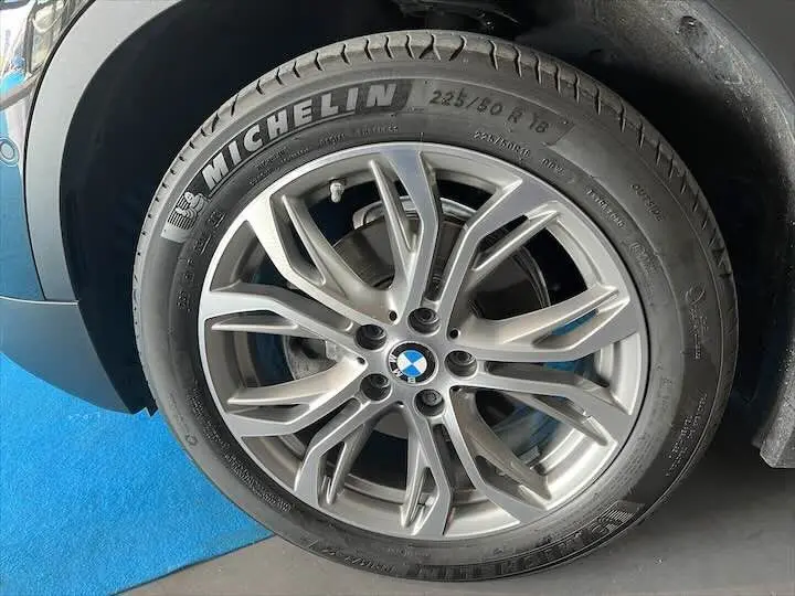 Gros plan sur la roue avant droite d'un BMW X2 noir métal avec jante alliage et pneu Michelin visible.