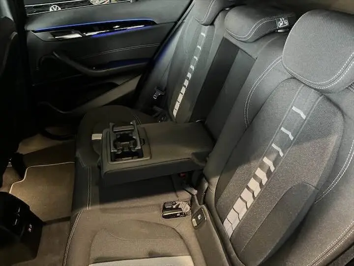 Vue intérieure arrière de la banquette noire avec accoudoir central et porte-gobelets du BMW X2 sDrive 18i 2022.