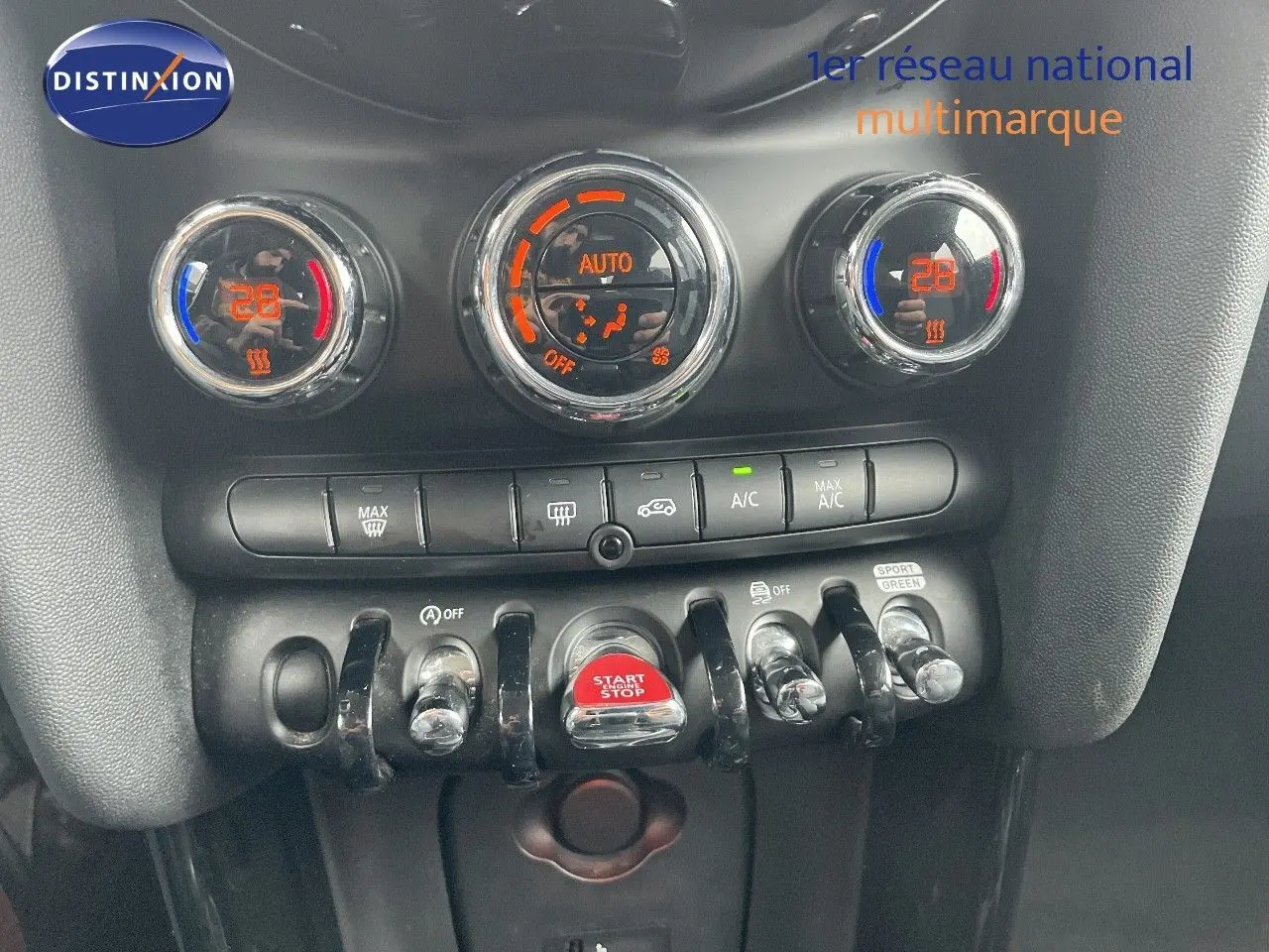 Gros plan sur la console centrale de la MINI 1.5 136CH STEPTRONIC 2023 avec commandes de climatisation et bouton start/stop rouge.