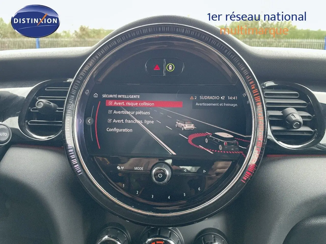 Vue rapprochée du tableau de bord de la MINI 2023, écran central rond affichant les alertes de sécurité, intérieur noir.