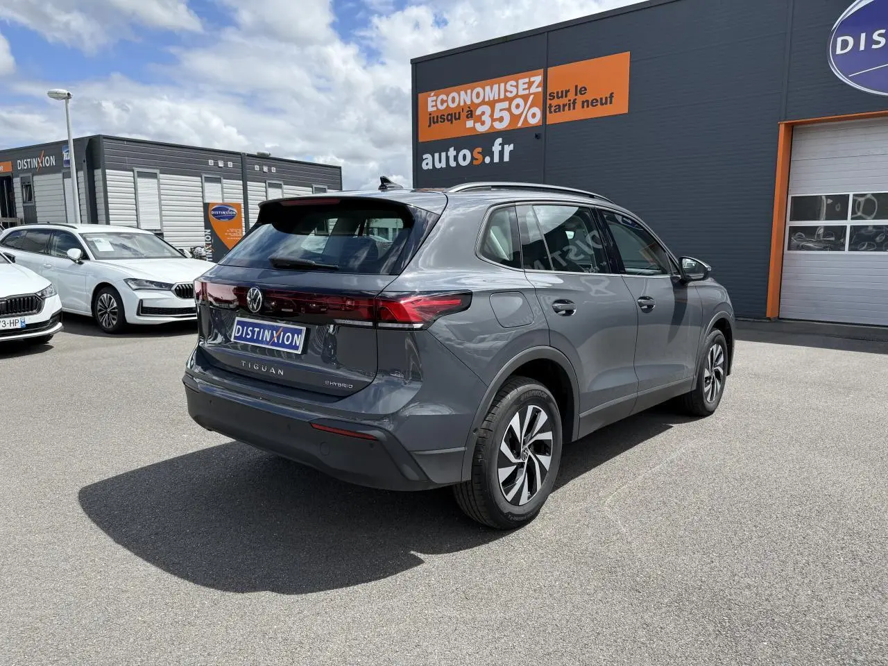 Vue 3/4 arrière droite d'un Volkswagen Tiguan gris dauphin hybride rechargeable avec jantes alliage et badge eHybrid.