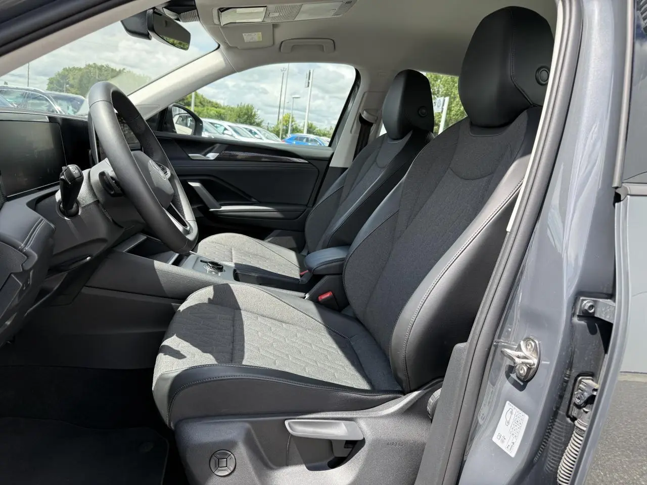 Vue intérieure côté conducteur du Volkswagen Tiguan 1.5 eHybrid gris Dauphin avec sièges tissu et cuir noir.