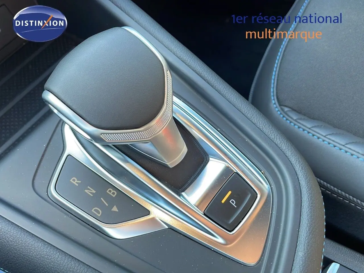 Le levier de boîte automatique du Renault Captur E-Tech hybride 2025, avec sellerie noire et surpiqûres bleues.