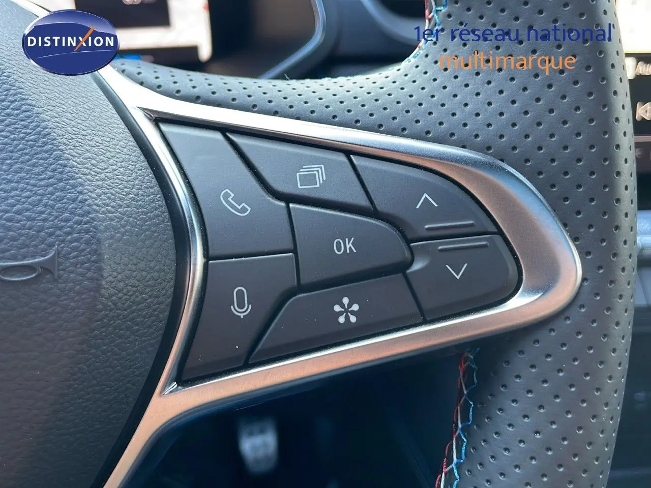 Gros plan sur les commandes multifonctions du volant perforé du Renault Captur E-Tech hybride bleu iron métal toit noir.