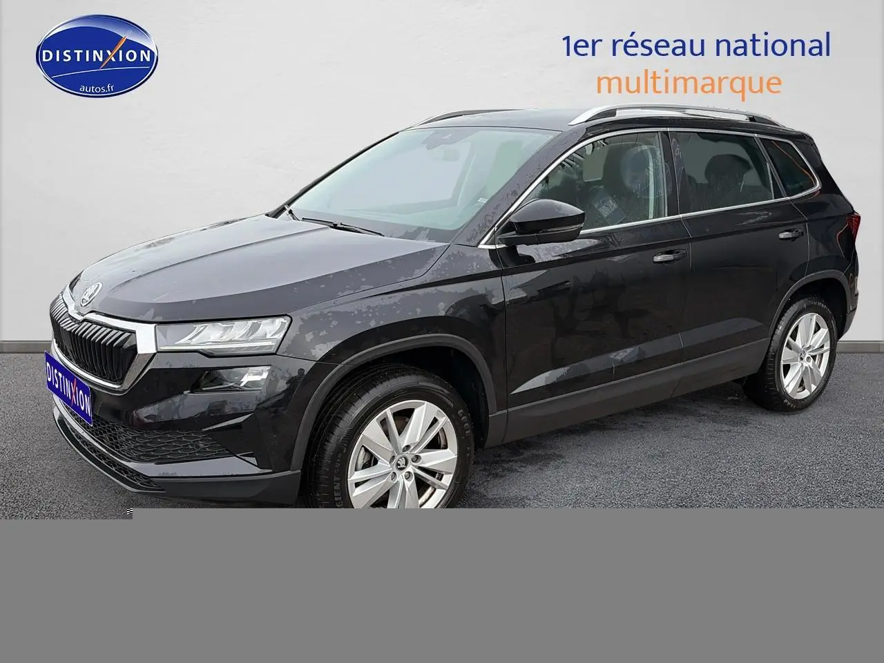 Vue 3/4 avant droite d’un Skoda Karoq noir 2025 avec jantes alu et barres de toit visibles.