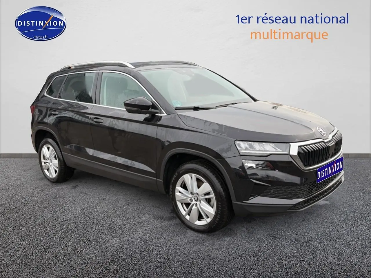 SUV SKODA KAROQ noir vu en 3/4 avant droit avec jantes alu et barres de toit visibles sur fond neutre.