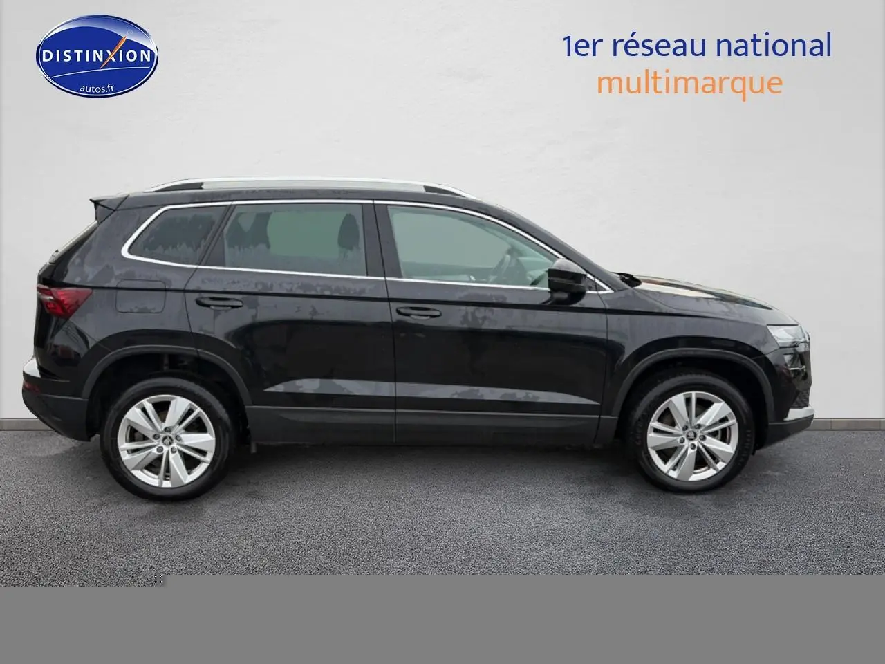 Vue de profil côté gauche d'un Skoda Karoq noir 2025 avec jantes alliage et barres de toit argentées.